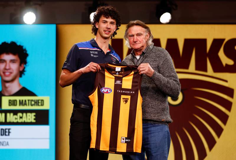 Debutant William McCabe receiving his Hawthorn guernsey in the locker room before the match.