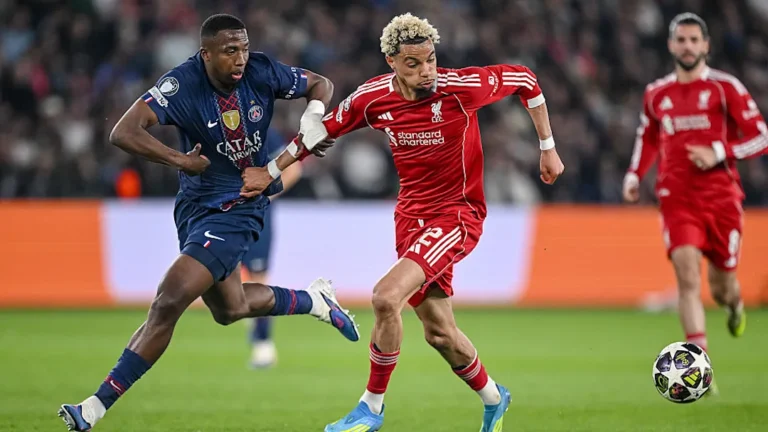 Liverpool and Paris Saint-Germain players shaking hands before a massive UEFA Champions League match under the stadium lights.