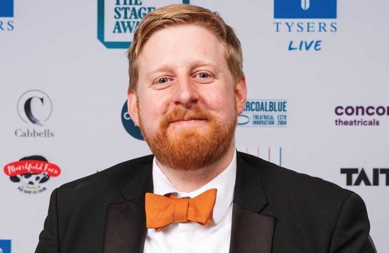 A tribute portrait of the late actor Michael Patrick smiling during a theatrical performance.