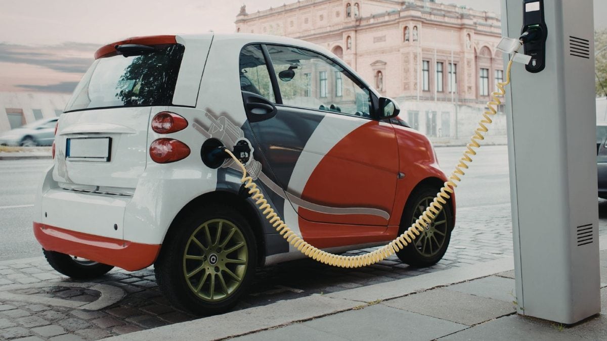 A bustling street in Bengaluru with various electric vehicles, including two-wheelers and cars, indicating the rapid adoption of EVs in the city.