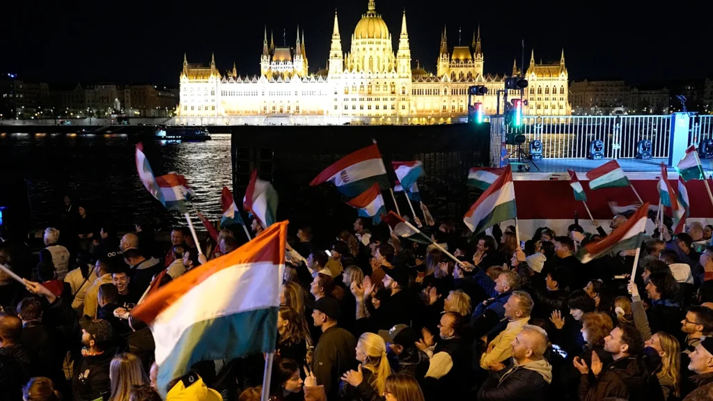 Péter Magyar addressing a massive crowd of cheering Tisza party supporters by the Danube River.