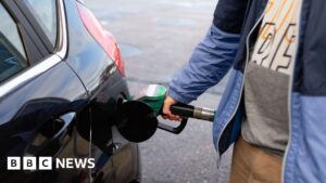 Man filling up car at petrol station, symbolizing high oil prices