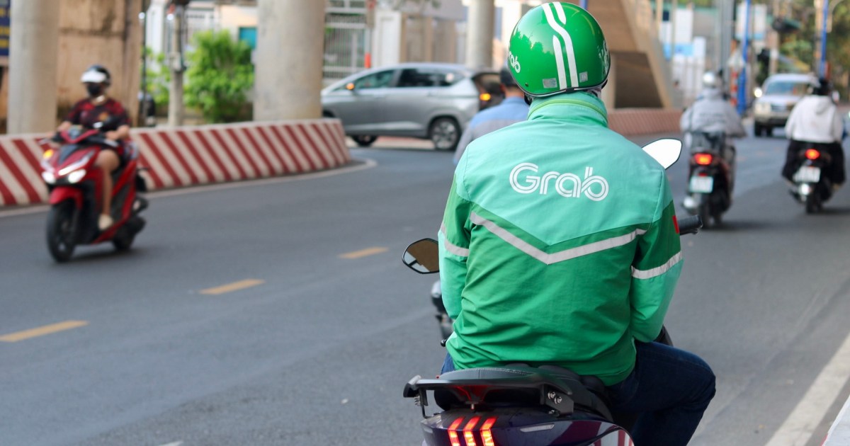 A Grab driver waits outside Thu Duc metro station in Ho Chi Minh City, Vietnam. The image captures the everyday scene of a gig worker, illustrating the context of the article's focus on rising fuel costs impacting the gig economy.