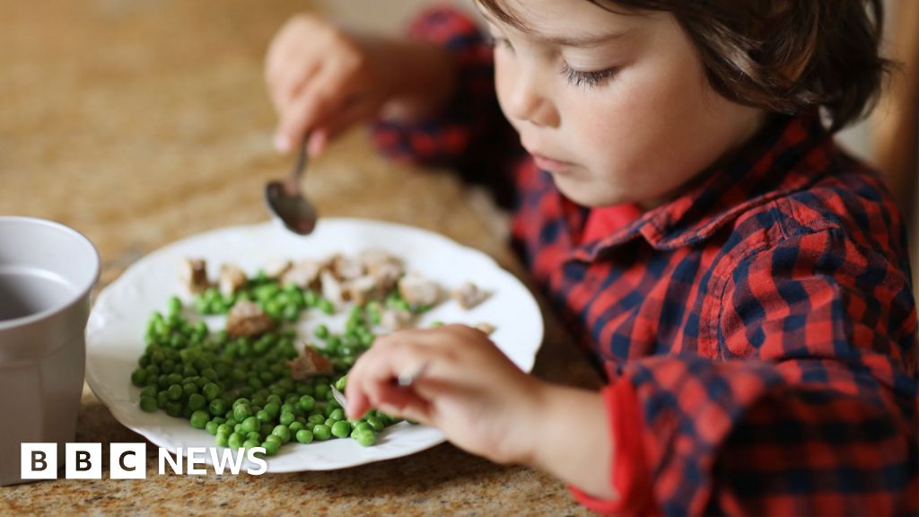 Child eating peas and mushrooms at a table, symbolizing global food security challenges.