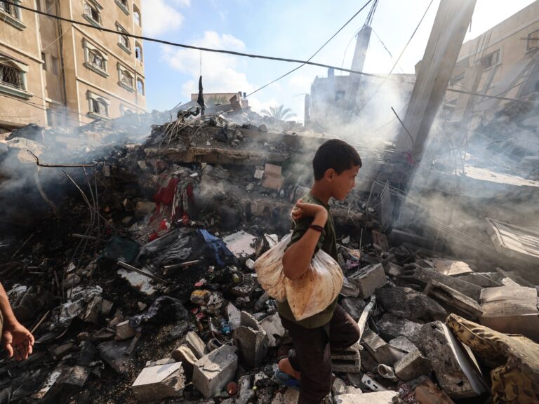 A Palestinian boy stands by the rubble of a residential building destroyed by an Israeli strike in central Gaza.