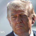 Donald Trump looking at the camera in a suit, suggesting a serious political discussion.