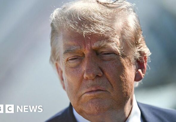 Donald Trump looking at the camera in a suit, suggesting a serious political discussion.