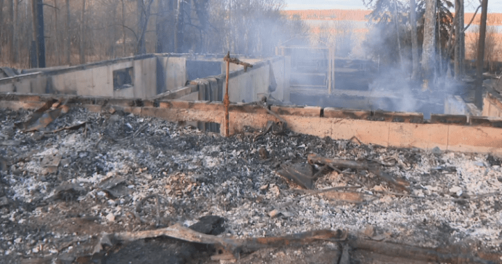 Aerial view of smoke rising from a wildfire near Sandy Beach, Alberta, with homes in the foreground.