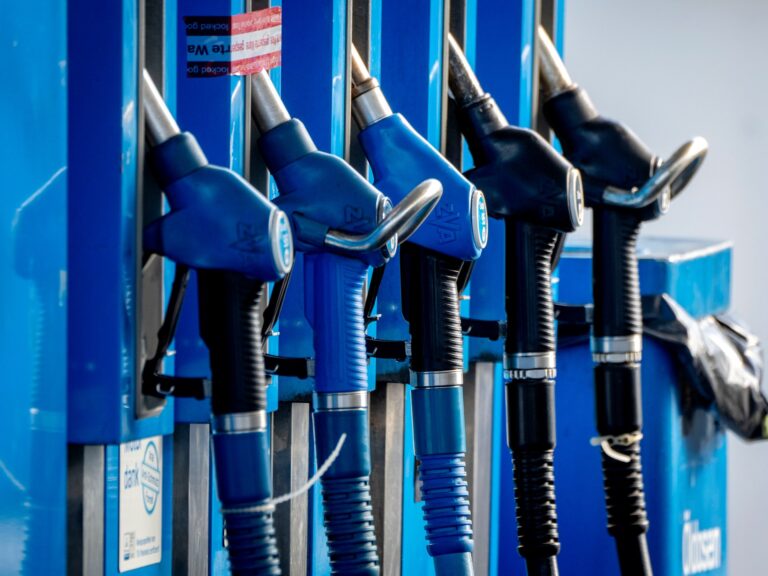 Pumps at a gas station with a headline about UAE increasing oil supplies.