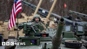 US soldiers on a tank in Germany, symbolic of the US military presence in Europe.