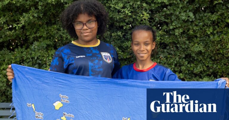Two young people holding a Cape Verde flag in front of greenery, embodying diaspora pride.