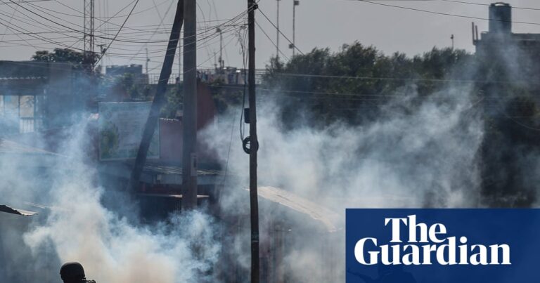Riot police and armed officers amidst teargas smoke and debris during protests against an Ebola quarantine center in Nanyuki, Kenya.