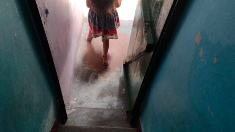 An eight-year-old girl in Delhi plays with a doll, symbolizing innocence amidst a family's fight for justice after her infant rape, highlighting systemic legal delays and their emotional toll.