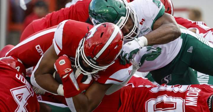 Saskatchewan Roughriders' Jameer Thurman attempts to tackle Calgary Stampeders quarterback Quincy Vaughn during a CFL game.