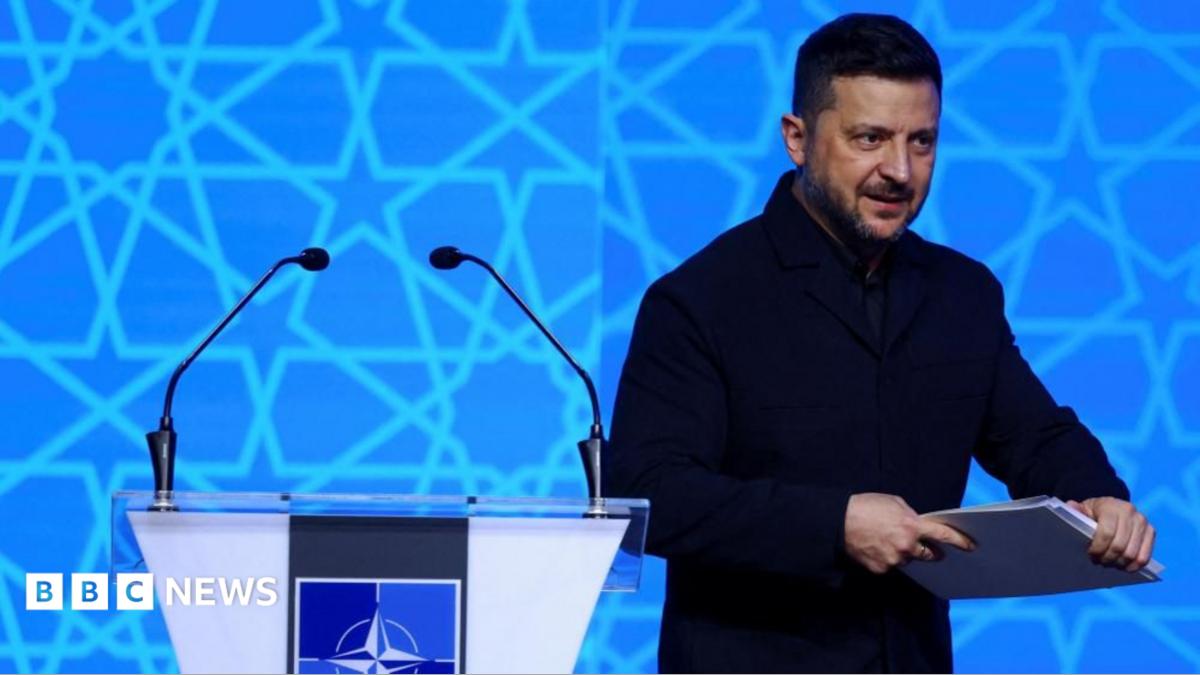 Ukrainian President Volodymyr Zelensky after addressing NATO, holding a binder of notes.