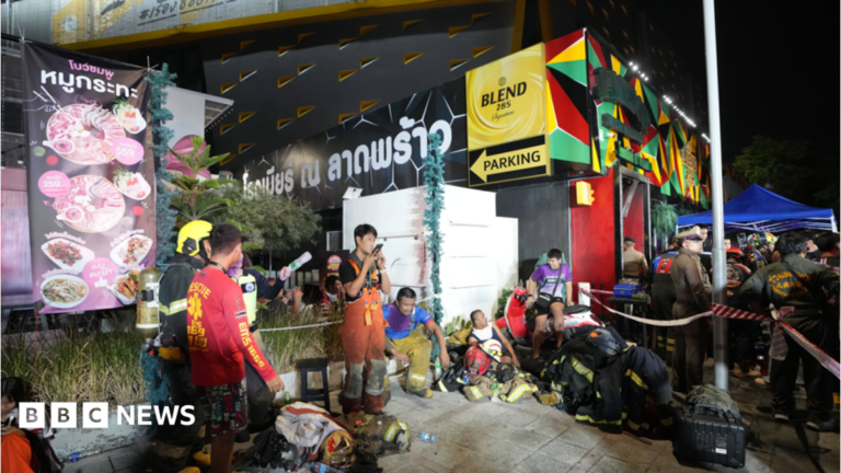 Image of firefighters outside the charred Bangkok bar venue after the blaze.