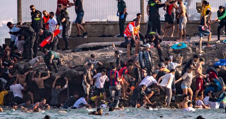 Image of migrants swimming towards Ceuta amid border chaos.