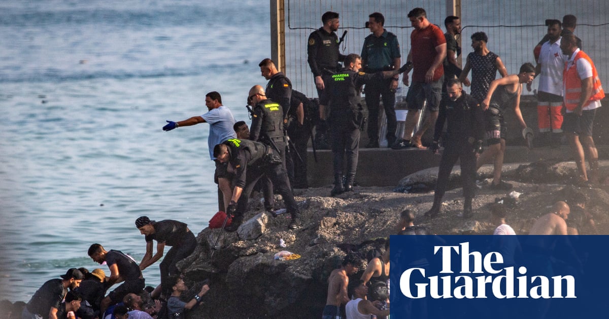 People climbing out of the sea onto a rocky shore in Ceuta