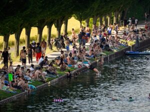 People sit by a canal during a heatwave in Europe.