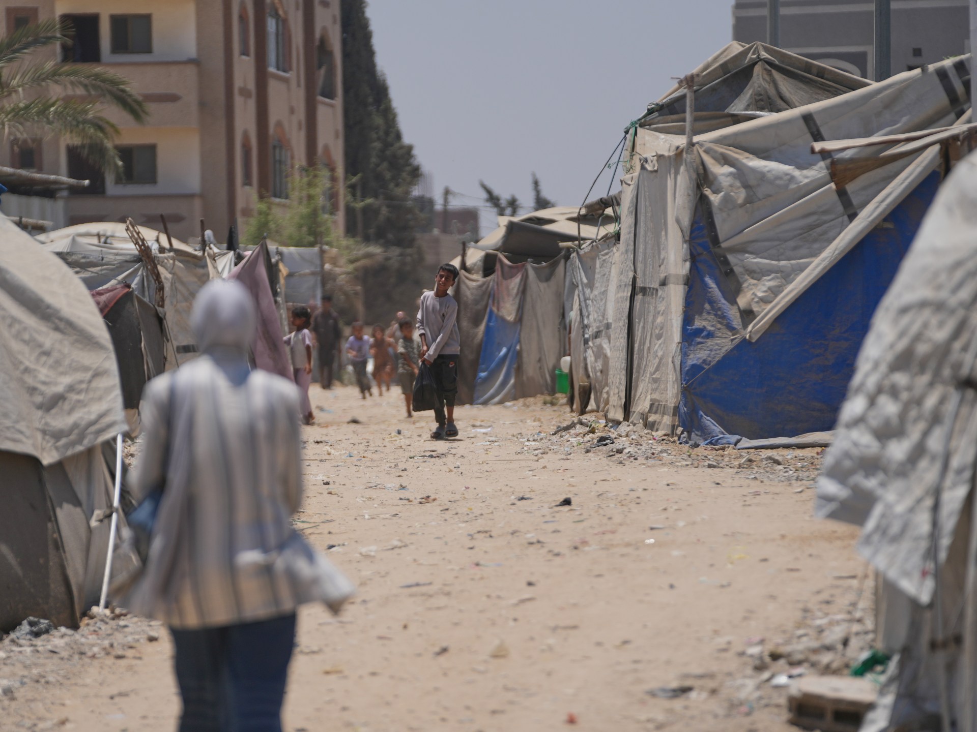 Displaced Palestinians walk amidst tents in Deir al-Balah, Central Gaza.