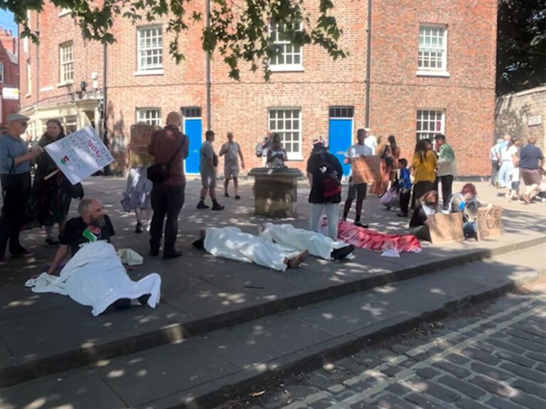 UK Christians protest calling for the Church of England to recognize genocide in Gaza, holding banners.