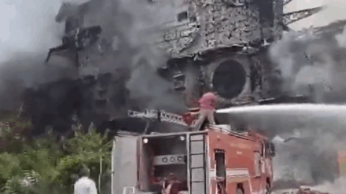 Image showing smoke billowing from the Kingdom of Dreams complex in Gurugram during a fire incident, with firefighters on the scene.