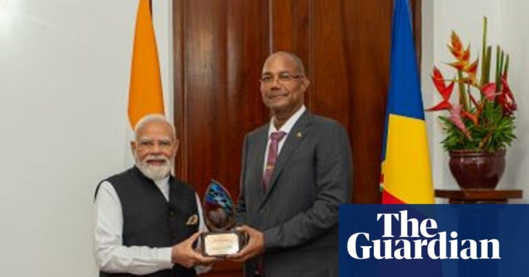 Indian Prime Minister Narendra Modi receiving an award from Seychelles President Patrick Herminie in front of national flags.