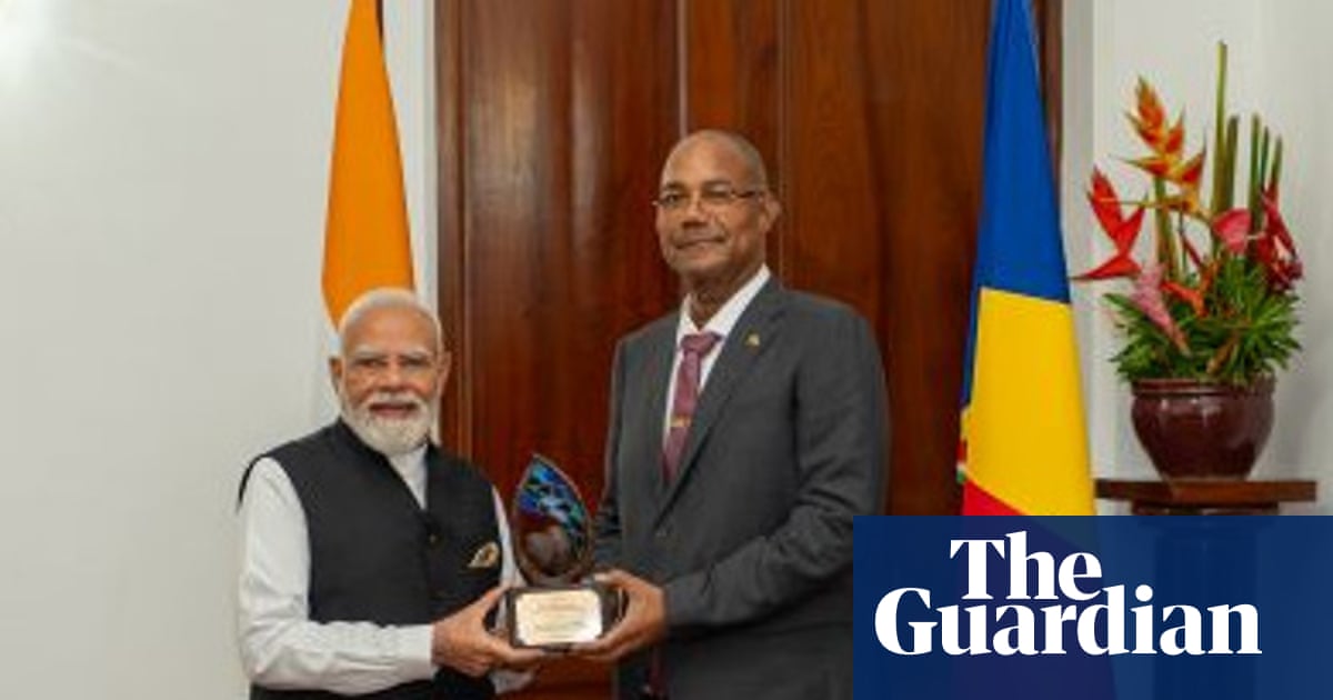 Indian Prime Minister Narendra Modi receiving an award from Seychelles President Patrick Herminie in front of national flags.