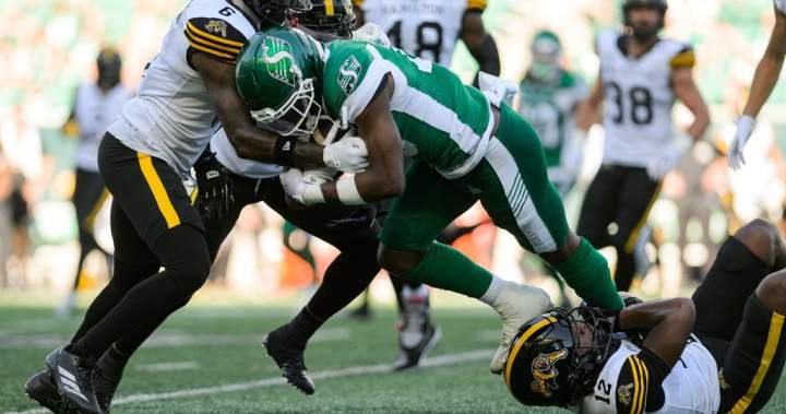 Saskatchewan Roughriders Samuel Emilus fighting for a first down against Hamilton Tiger-Cats' Zamari Walton during a CFL game.