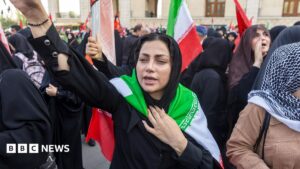 Image of an armed IRGC member during a funeral in Tehran, Iran, July 2026, amidst rising US-Iran tensions.