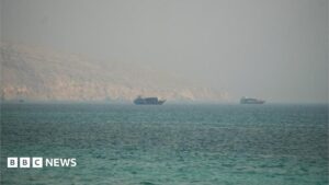 Image showing the Strait of Hormuz with commercial vessels navigating past rocky mountains