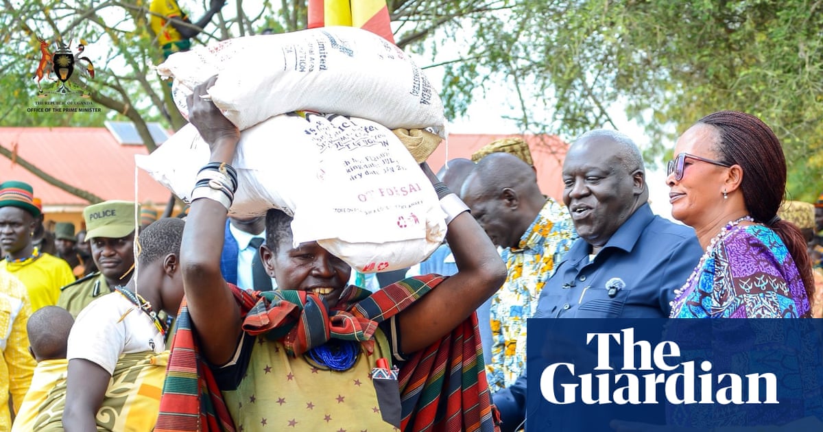 A Ugandan woman carrying grain on her head during food distribution, highlighting the crisis.