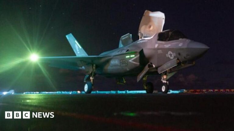 Image of a US F-35 fighter jet on an aircraft carrier under a night sky, following US strikes on Iran.