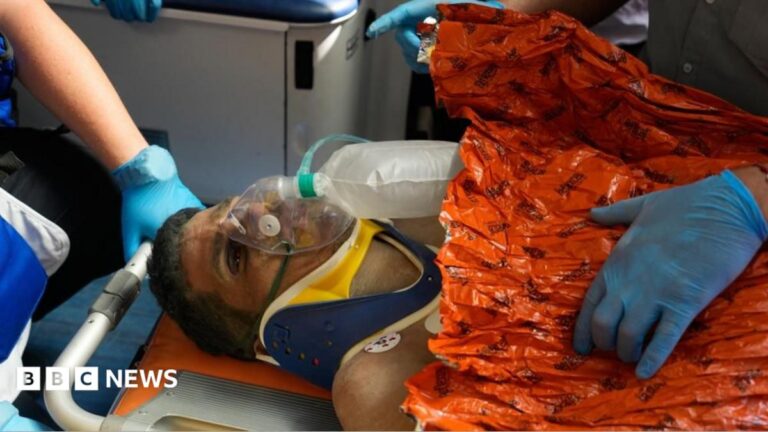 Man Hernán Gil, a Venezuela quake survivor, rescued from rubble after eight days, lying on a stretcher with an oxygen mask and orange blanket.