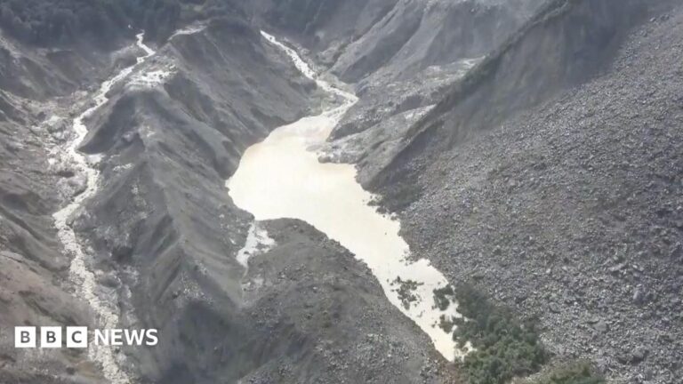Image showing a barrier lake formed in a mountainous region near the Nepal-Tibet border, with an arrow indicating the direction of a flash flood.