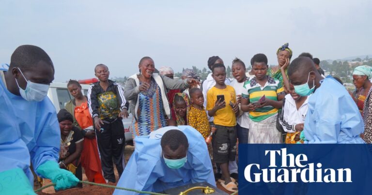 People in protective clothing lower the coffin of an Ebola victim into a grave in Bunia, Ituri province.