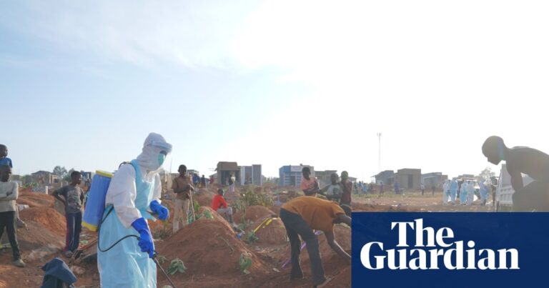 Health worker spraying disinfectant in a freshly dug grave in Bunia, DRC, amidst an Ebola outbreak.