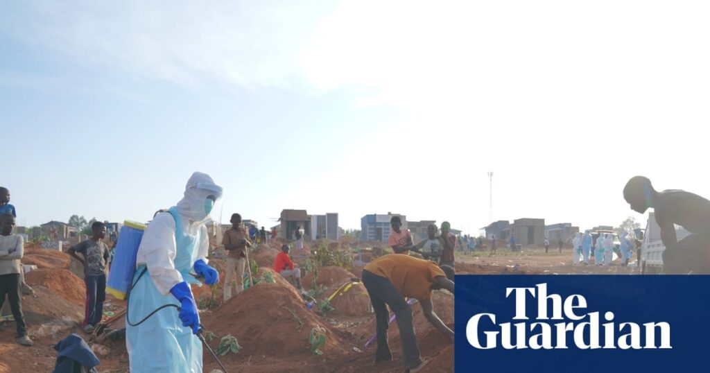 A health worker in protective gear sprays disinfectant into a freshly dug grave during the Ebola outbreak in Bunia, DRC.