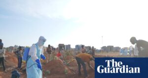 A health worker in protective gear sprays disinfectant into a freshly dug grave during the Ebola outbreak in Bunia, DRC.