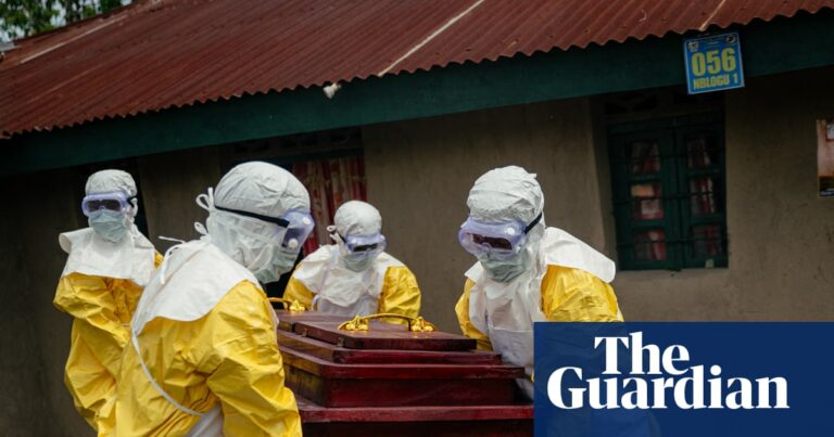 Members of the Congolese Red Cross team in PPE carry a coffin of a suspected Ebola victim.