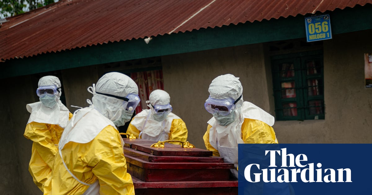 Members of the Congolese Red Cross team in PPE carry a coffin of a suspected Ebola victim.