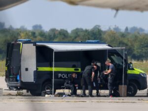 Image of drone near airport runway, illustrating European drone incursions and the new level of danger. Police officers examining a drone near an Antonov cargo plane at Leipzig/Halle Airport.