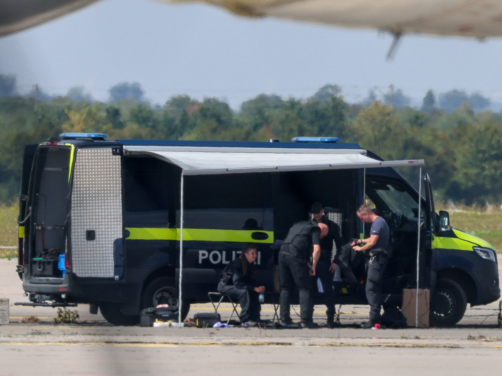 Image of drone near airport runway, illustrating European drone incursions and the new level of danger. Police officers examining a drone near an Antonov cargo plane at Leipzig/Halle Airport.