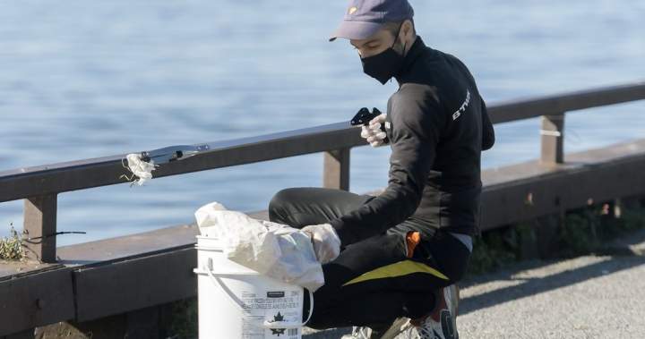 A man picking up trash along the St. Lawrence River during a cleanup event.