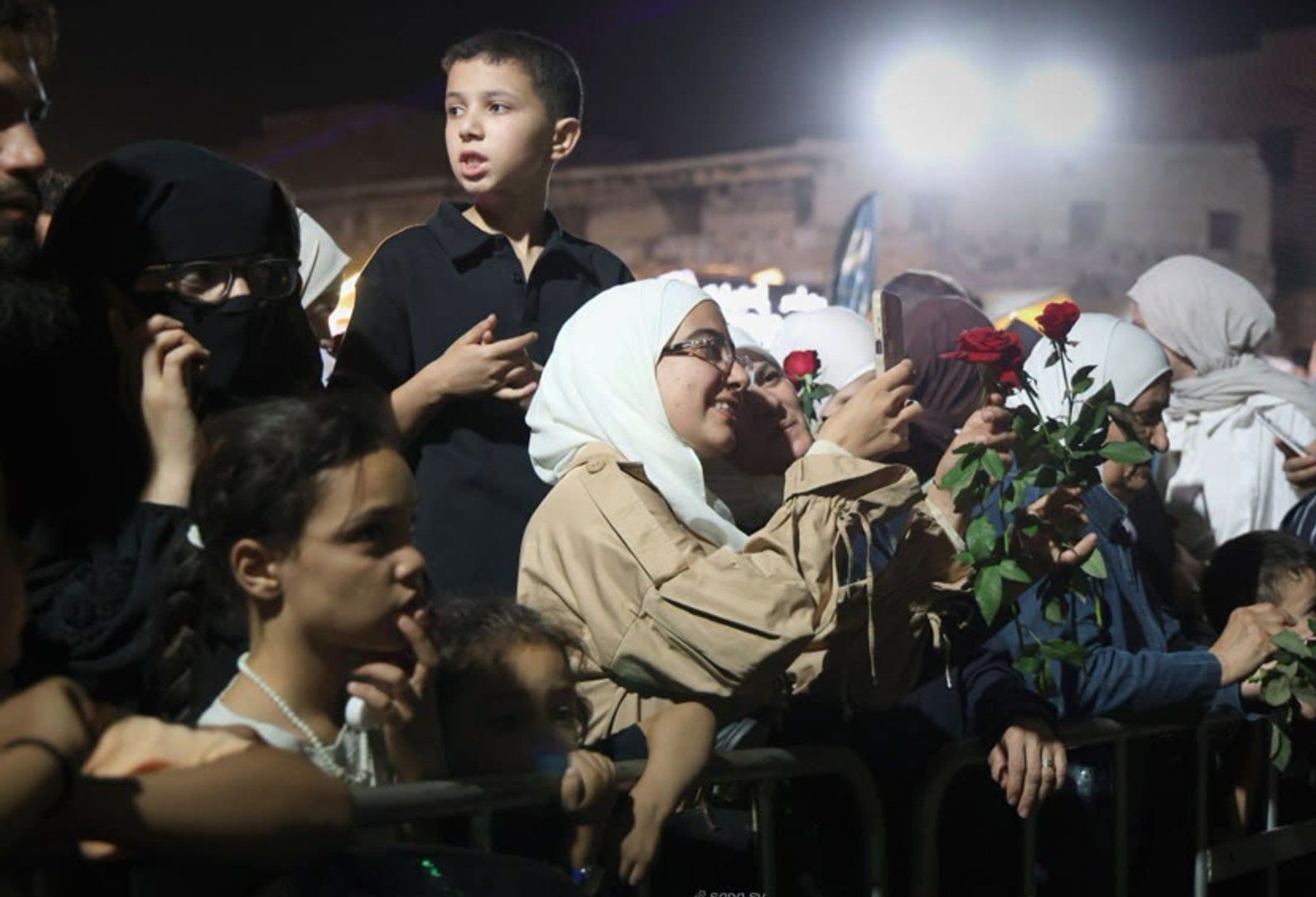 Syrian army helicopters dropping roses over a festival crowd at Damascus Citadel, symbolizing a new era of peace and cultural revival in Syria.