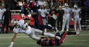 Montreal Alouettes players tackling a B.C. Lions player during intense CFL action.