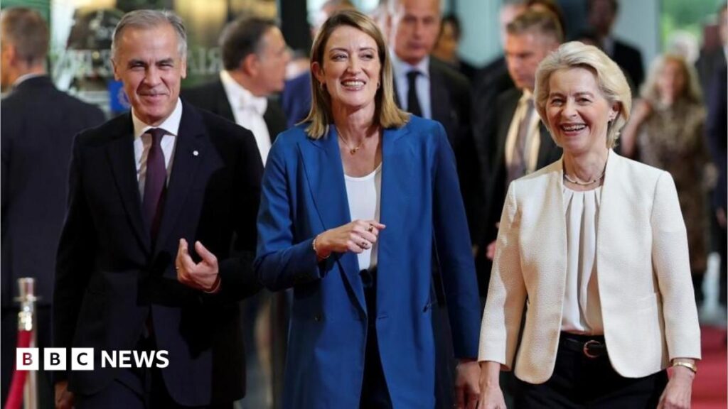 Image shows Canadian Prime Minister Mark Carney walking with European Parliament President Roberta Metsola and Ursula von der Leyen at the European Parliament.