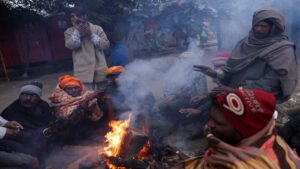 People warming themselves by a fire in Delhi as temperatures drop unseasonably in September.