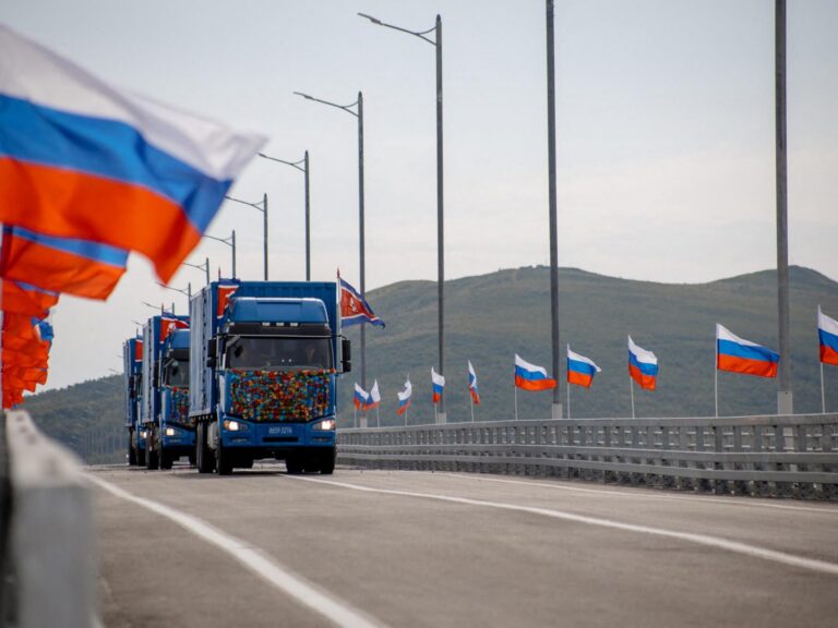 New Russia-North Korea road bridge over the Tumen River with national flags waving and trucks crossing.